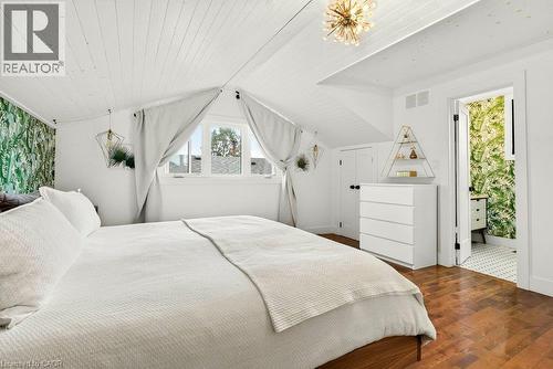 Sloped wood-paneled ceiling, wood-finish flooring, two large windows, and a built-in closet with a solid door - 9 Midway Street, Hamilton, ON 