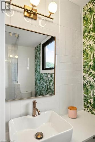 White subway tile, a rectangular vessel sink with a bronze-finish faucet, and a wall-mounted brass-finish light fixture - 9 Midway Street, Hamilton, ON 