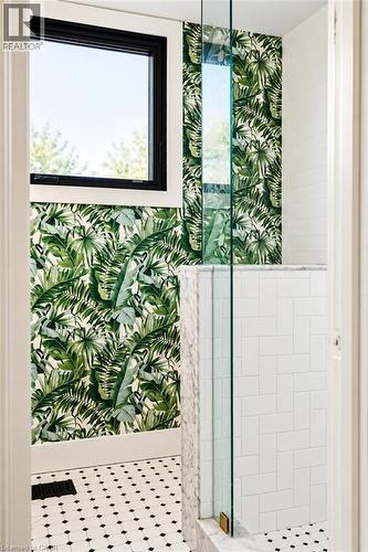 Black-framed window, botanical wall covering, black and white mosaic tile flooring, white subway tile shower, and clear glass shower enclosure - 9 Midway Street, Hamilton, ON 