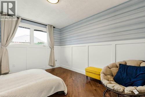 Hardwood-style flooring, white wainscoting, horizontally striped wall treatment, window with natural light, and a flush-mount ceiling light - 9 Midway Street, Hamilton, ON 