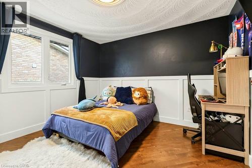 Wood-finish flooring, white wainscoting, dark accent wall, white window trim, and a patterned ceiling - 9 Midway Street, Hamilton, ON 