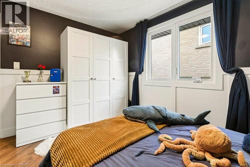 Hardwood-finish flooring, white paneled lower walls, contrasting dark accent wall, and a large window with white trim - 9 Midway Street, Hamilton, ON 