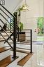 White main entry door with dark hardware, glossy tile flooring, wood-tread staircase with black metal railing, and a geometric pendant light fixture - 9 Midway Street, Hamilton, ON 