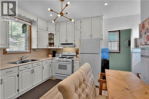 White cabinetry with brushed nickel hardware, stainless steel double basin sink, neutral countertops, gas range, and a contemporary brass chandelier - 7 Halls Avenue, Brantford, ON 