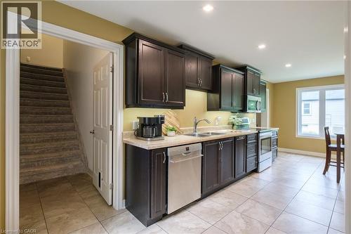 Contemporary kitchen featuring dark wood cabinetry, stainless steel appliances, light-toned countertops, and recessed lighting - 78 Oak Street, Simcoe, ON 