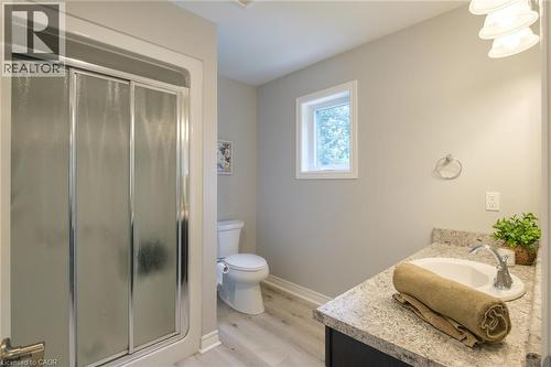 Sliding glass shower enclosure, single vanity with integrated sink, stone-finish countertop, wood-finish flooring, and a single window - 78 Oak Street, Simcoe, ON 
