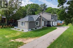 Gray siding exterior with white trim, multiple windows, and a paved driveway - 