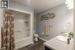 Tub/shower combination with a single-handle faucet, vanity with an integrated sink, and wood-finish flooring - 