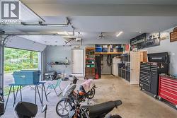 Attached garage with an overhead door, smooth concrete flooring, built-in shelving, and a pedestrian door - 