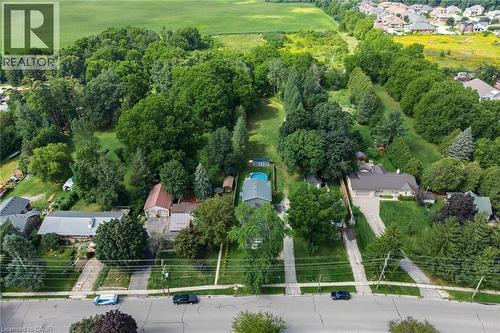 Expansive property featuring mature trees, a private swimming pool, and multiple detached structures - 78 Oak Street, Simcoe, ON 