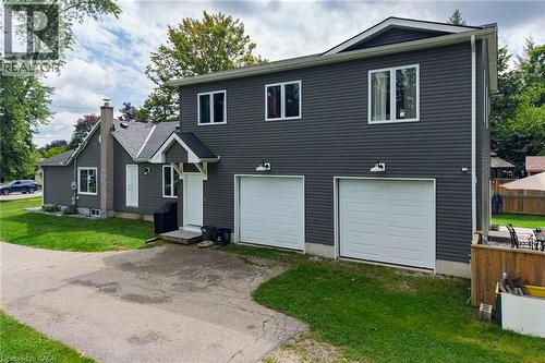 Two-story property with dark gray siding, a prominent brick chimney, two white garage doors, and a paved driveway - 78 Oak Street, Simcoe, ON 