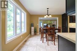 Tile flooring, multi-pane window, open doorway, dark wood-finish cabinetry, and light-toned countertops - 