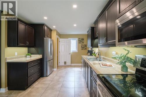Contemporary kitchen featuring dark wood cabinetry, stainless steel appliances, light-toned countertops, and recessed lighting - 78 Oak Street, Simcoe, ON 
