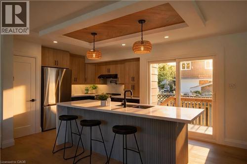Kitchen featuring wood-finish cabinetry, stainless steel appliances, a center island with integrated sink, and recessed lighting - 3028 Eva Drive, Burlington, ON 
