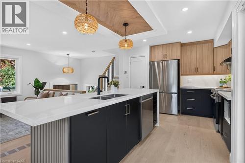 Kitchen featuring a large island with white countertop, dual basin sink with matte black faucet, and integrated dishwasher - 3028 Eva Drive, Burlington, ON 