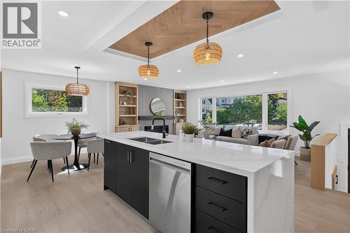 Open-concept living space with light wood-finish flooring, a kitchen island featuring a stainless steel dishwasher, and recessed lighting - 3028 Eva Drive, Burlington, ON 