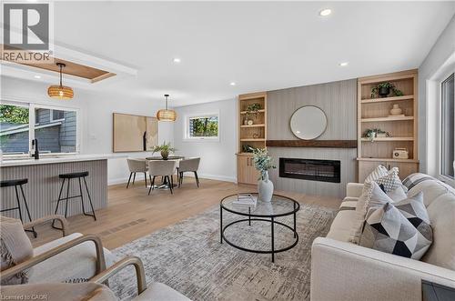Open-concept living area featuring wood-finish flooring, recessed lighting, and a built-in fireplace with custom shelving - 3028 Eva Drive, Burlington, ON 