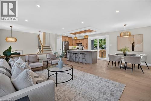 Open-concept living space with light wood-finish flooring, recessed lighting, and a kitchen island with seating - 3028 Eva Drive, Burlington, ON 