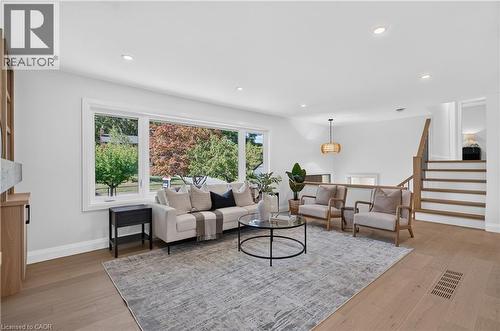 Expansive living area featuring wood-finish flooring, recessed lighting, and a large picture window - 3028 Eva Drive, Burlington, ON 