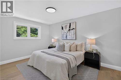 Light wood-finish flooring, white trim, and a window with a green exterior - 3028 Eva Drive, Burlington, ON 