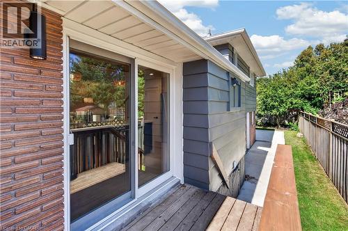Siding with horizontal paneling, brick-finish accent wall, outdoor wall-mounted lighting, and a sliding glass door - 3028 Eva Drive, Burlington, ON 