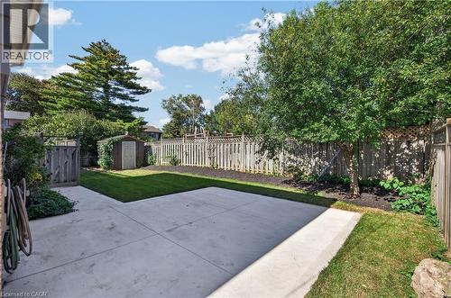 Expansive concrete patio with a manicured lawn, established landscaping, and a privacy fence - 3028 Eva Drive, Burlington, ON 