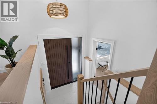 Entryway featuring a vertically paneled door with frosted glass side panel, a woven pendant light fixture, and a white tile floor - 3028 Eva Drive, Burlington, ON 
