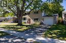 Two-story residence with a light-colored brick exterior, attached single-car garage, red entry door, and a mature shade tree in the front yard - 52 Brier Park Road, Brantford, ON 