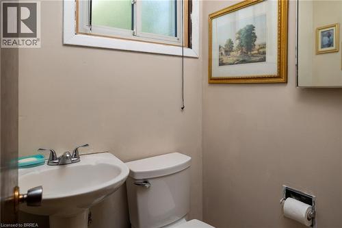 Pedestal sink with dual-handle chrome faucet, white commode, and a window with frosted glass - 52 Brier Park Road, Brantford, ON 