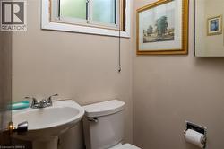 Pedestal sink with dual-handle chrome faucet, white commode, and a window with frosted glass - 