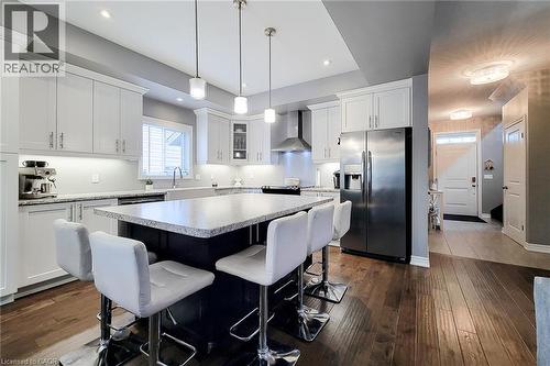 Kitchen featuring light-finish cabinetry, stainless steel appliances, a dark-toned island with a light-toned countertop, and wood-finish flooring - 4274 Sixth Avenue, Niagara Falls, ON 