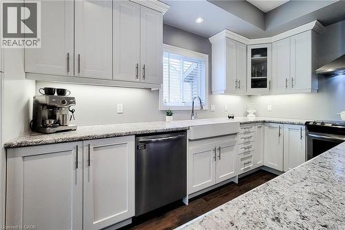 White shaker cabinetry, stone countertops, stainless steel appliances, apron-front sink, and rich wood-finish flooring - 4274 Sixth Avenue, Niagara Falls, ON 