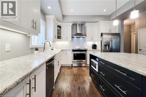 White shaker cabinetry, stainless steel appliances, speckled stone countertops, wood-finish flooring, and a central island with integrated microwave - 4274 Sixth Avenue, Niagara Falls, ON 