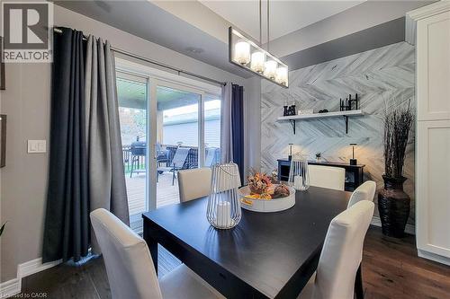 Wood-finish flooring, accent wall with a herringbone pattern, linear light fixture, built-in cabinetry, and sliding glass door - 4274 Sixth Avenue, Niagara Falls, ON 