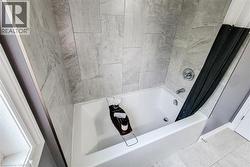 White soaking tub with chrome fixtures, surrounded by large format gray tile - 