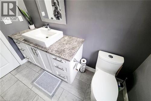 White vanity with brushed nickel hardware, rectangular vessel sink, patterned countertop, and light gray tile flooring - 4274 Sixth Avenue, Niagara Falls, ON 