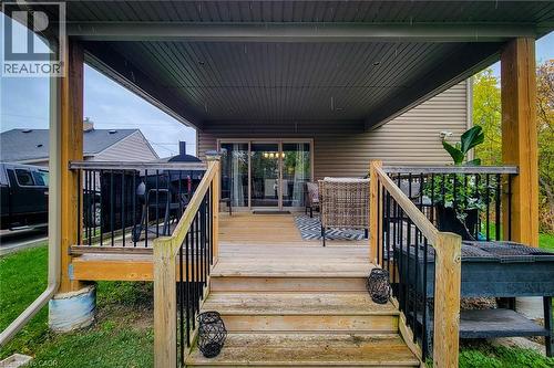 Covered deck with wood-finish stairs, durable railings, and sliding glass door access - 4274 Sixth Avenue, Niagara Falls, ON 