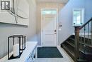 Entryway featuring a solid wood door with transom window, light wood-finish flooring, and a dark wood staircase with wrought iron balusters - 4274 Sixth Avenue, Niagara Falls, ON 