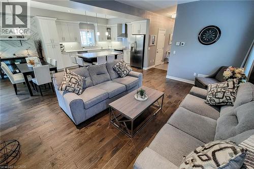 Wood-finish flooring throughout, white upper and lower cabinetry, stainless steel appliances, a kitchen island with seating, and recessed lighting - 4274 Sixth Avenue, Niagara Falls, ON 