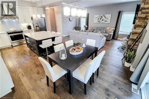 Open-concept main living area with wood-finish flooring, a kitchen island with seating, stainless steel appliances, a stacked stone accent wall, and recessed lighting - 4274 Sixth Avenue, Niagara Falls, ON 