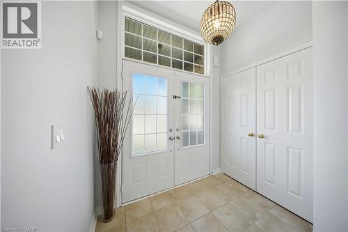 White double-entry doors with frosted glass panels, transom window, recessed lighting, and a decorative light fixture - 3352 Hiscott Avenue, Burlington, ON 