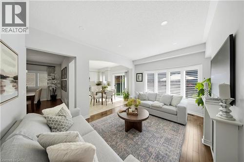 Recessed lighting illuminates the living area, featuring wood-finish flooring and crown molding - 3352 Hiscott Avenue, Burlington, ON 