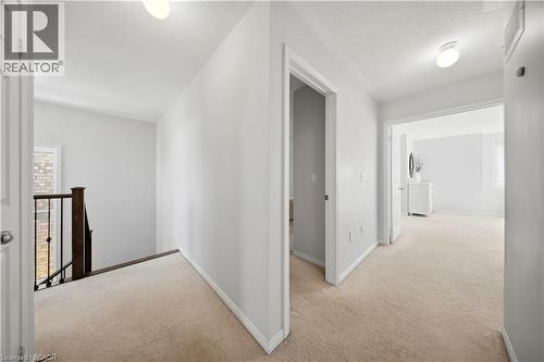 Carpeted hallway with white walls, recessed lighting, and a dark wood and iron stair railing - 3352 Hiscott Avenue, Burlington, ON 