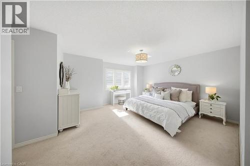 Light-toned wall paint throughout, plush carpet flooring, window with white plantation shutters, and a decorative ceiling light fixture - 3352 Hiscott Avenue, Burlington, ON 