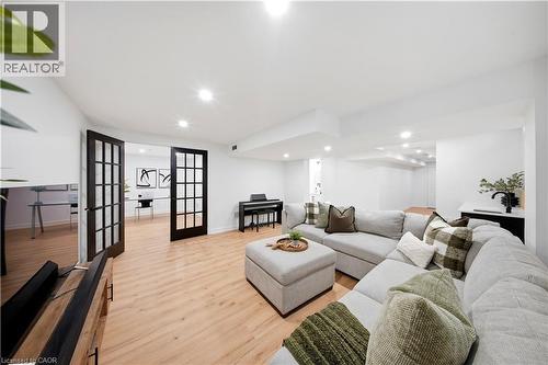 Spacious room with wood-finish flooring, recessed lighting, and black French doors leading to an additional space - 3352 Hiscott Avenue, Burlington, ON 