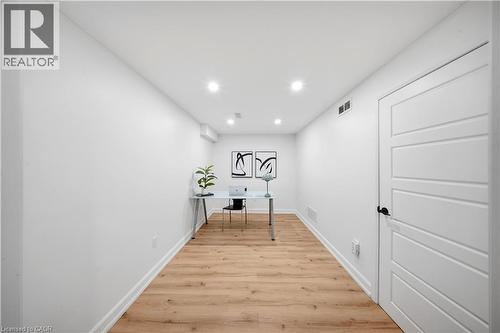 Wood-finish flooring, recessed lighting, white walls, and a four-panel interior door with matte black hardware - 3352 Hiscott Avenue, Burlington, ON 