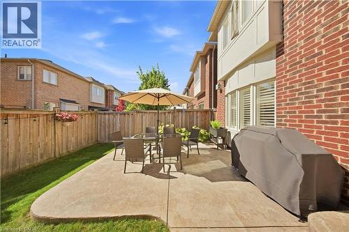 Private backyard featuring a concrete patio, wood fencing, and a manicured lawn - 3352 Hiscott Avenue, Burlington, ON 