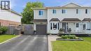Light-colored siding exterior with a dark roof, featuring a bay window, an attached single-car garage, a paved driveway, and a front porch - 4804 John Street, Beamsville, ON 