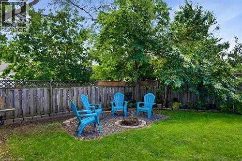 Expansive backyard with a manicured lawn, dedicated fire pit area, and mature trees providing natural screening - 4804 John Street, Beamsville, ON 