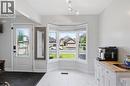 White entry door with decorative glass inserts, bay window with multiple panes, white tile flooring, and track lighting - 4804 John Street, Beamsville, ON 